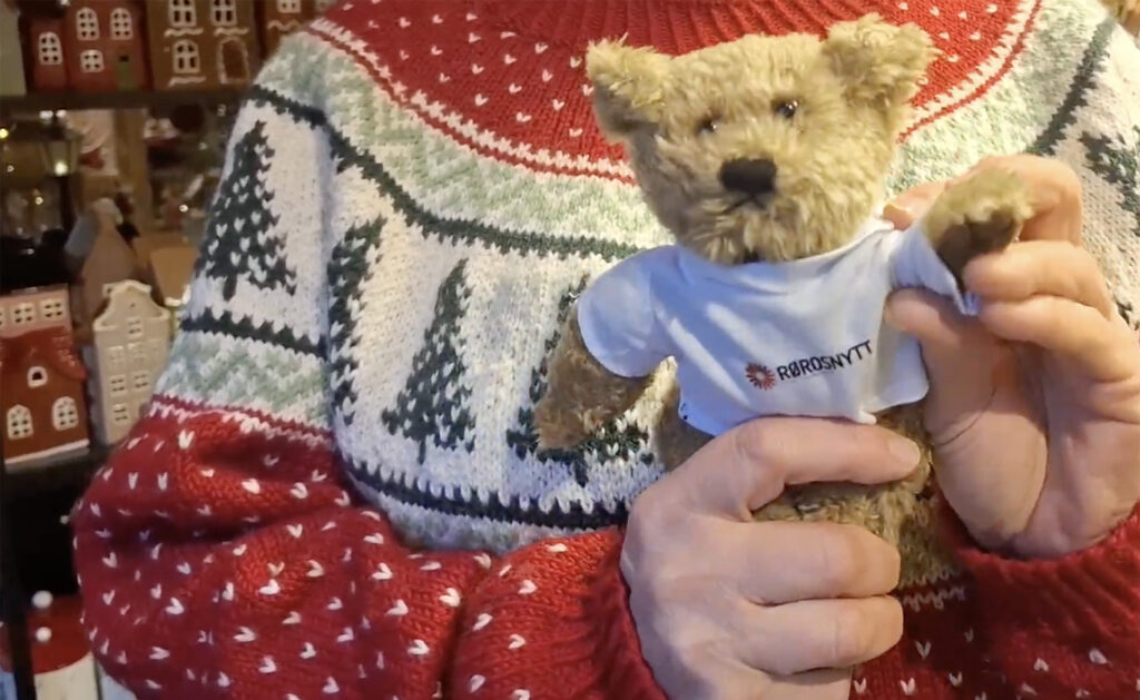 Med litt hjelp fra Ragnhild Bjerkan vinker Rørosnytt-Bamsen i håp om å bli fotografert i butikken Lille Røros i dag.
Foto: Tore Østby Lille Røros