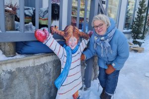 Driver av Lille Røros, Ragnhild Bjerkan  har laget Pippi, som står utenfor butikken. Hunden Kompis sto på trappen da bilde ble tatt. Foto: Tove Østby