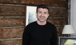 Eiendomsmegler hos Nylander & Partners Røros, Yama Meskinyar fremfor tømmerveggen i Bergmannsgata 26. Foto: Tove Østby