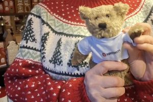 Med litt hjelp fra Ragnhild Bjerkan vinker Rørosnytt-Bamsen i håp om å bli fotografert i butikken Lille Røros i dag.
Foto: Tore Østby